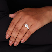 Hand wearing a diamond ring on a black background