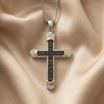 14k white gold black moissanite cross pendant necklace. A silver and gold cross pendant necklace with black gemstone detailing, displayed on a draped beige satin fabric background.