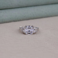 Silver ring with a large central gemstone on a neutral background