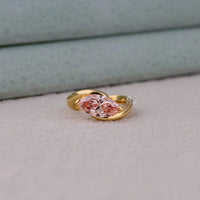 Gold ring with a pink gemstone on a light gray surface