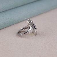 Silver ring with intricate design on a light gray surface