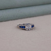 Diamond ring with blue gemstones on a neutral background