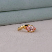 Gold ring with a pink gemstone on a light gray background