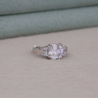 Silver ring with a large diamond on a beige surface