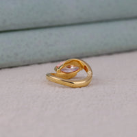 Gold ring on a light gray surface with a neutral background