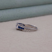 Silver ring with blue gemstones on a light gray surface