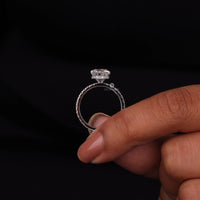 Silver ring with a diamond held by a hand against a black background