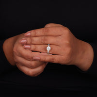 Close-up of a hand wearing a diamond ring on a black background