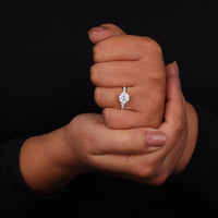 Hand holding another hand wearing a diamond ring against a black background