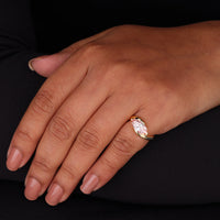 Hand wearing a rose gold ring with a clear gemstone on a black background