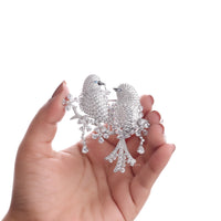 Silver bird-shaped brooch held in a hand against a white background, Elegant Love Bird Jewelry Brooch – Round & Marquise CZ Gemstone Pin