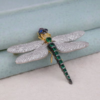 Decorative dragonfly with gemstones on a light blue background, Emerald, Ruby, Sapphire & CZ Dragonfly Brooch – White & Yellow Gemstone Jewelry Pin