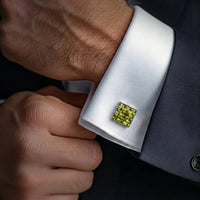 Cufflink with a green gemstone on a white cuff against a dark suit background