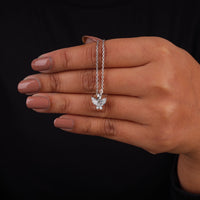 Hand holding a silver butterfly necklace against a black background, Butterfly Inspired Pendant Necklace – Marquise & Round Moissanite Necklace in 14K Gold