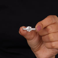 Hand holding a diamond ring against a black background