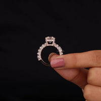 Diamond ring held between fingers against a black background
