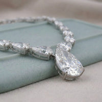 Silver bracelet with large teardrop-shaped diamonds on a light blue surface