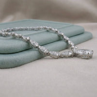 Silver bracelet with clear stones on a light blue fabric background
