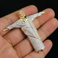 Gold and diamond-encrusted religious pendant held in a hand against a black background