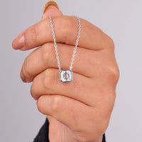 Hand holding a silver necklace with a diamond pendant against a gray background, Dainty Solitaire Moissanite Pendant For Women, Sparkling Asscher Cut Engagement Necklace, Modern Bezel Moissanite Bridal Jewelry