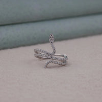 Silver snake-shaped ring with gemstones on a neutral background