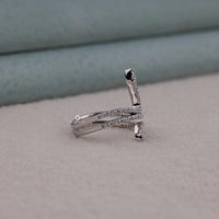 Silver ring with small diamonds on a light gray surface