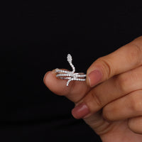 Silver ring with diamond accents held between fingers against a black background