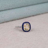 Diamond ring with blue gemstone setting on a light pink surface, Vintage Inspired Old Mine Cut CZ Ring – Sapphire Halo Art Deco Statement Ring