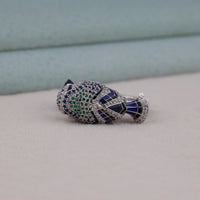 Jewelry item with green and blue gemstones on a neutral background