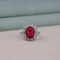 Ring with a red gemstone and diamond accents on a neutral background