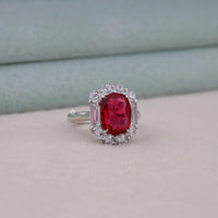 Ring with a red gemstone and diamond-like stones on a neutral background