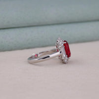 Silver ring with a red gemstone on a light gray surface