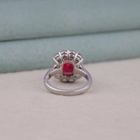 Silver ring with a red gemstone on a light gray surface