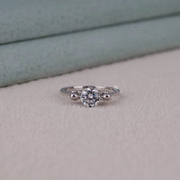 Silver ring with a diamond on a light gray surface