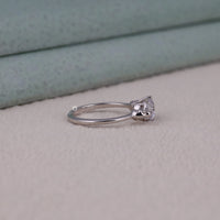 Silver ring with a diamond on a light gray surface