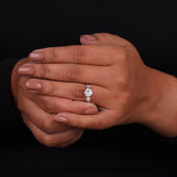 Close-up of a hand wearing a diamond ring on a black background