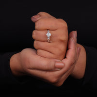 Close-up of a hand wearing a diamond ring with a black background