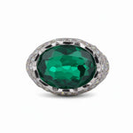 Ring with a large green gemstone and silver accents on a white background