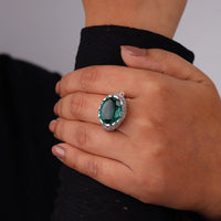Hand wearing a ring with a green gemstone on a neutral background, Antique Oval Emerald CZ Engagement Ring, Filigree Vintage Statement Ring for Women