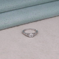 Silver ring with a diamond on a light gray surface, vintage moissanite ring,
milgrain engagement ring