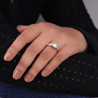 Hand wearing a diamond ring on a dark background, five stone moissanite ring