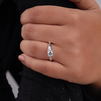 Close-up of a hand wearing a silver ring with a diamond on a black background, vintage style engagement ring