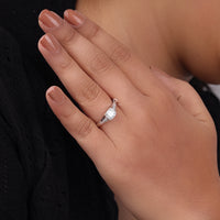 Close-up of a hand wearing a diamond ring with a blurred background, round moissanite ring, antique inspired bridal ring