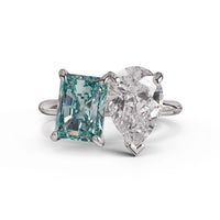 Ring with green emerald-cut gemstone and clear pear-shaped gemstone on a white background, White Pear & Green Radiant Moissanite Toi Et Moi Engagement Ring