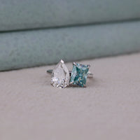 Two diamond rings with different cut styles on a neutral background, Toi Et Moi Engagement Ring – White Pear & Green Radiant Moissanite Wedding Jewelry