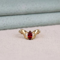 Gold ring with a red gemstone on a light pink surface
