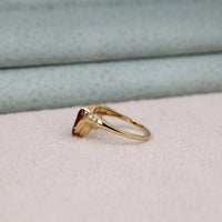 Gold ring with a red gemstone on a light fabric background