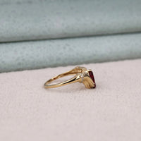 Gold ring with a red gemstone on a light gray surface