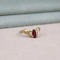 Gold ring with a red gemstone on a light gray background