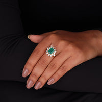 Hand wearing a ring with an emerald and diamonds on a black background, 14K Yellow Gold Green Emerald Cut CZ Engagement Ring – Classic Wedding Ring